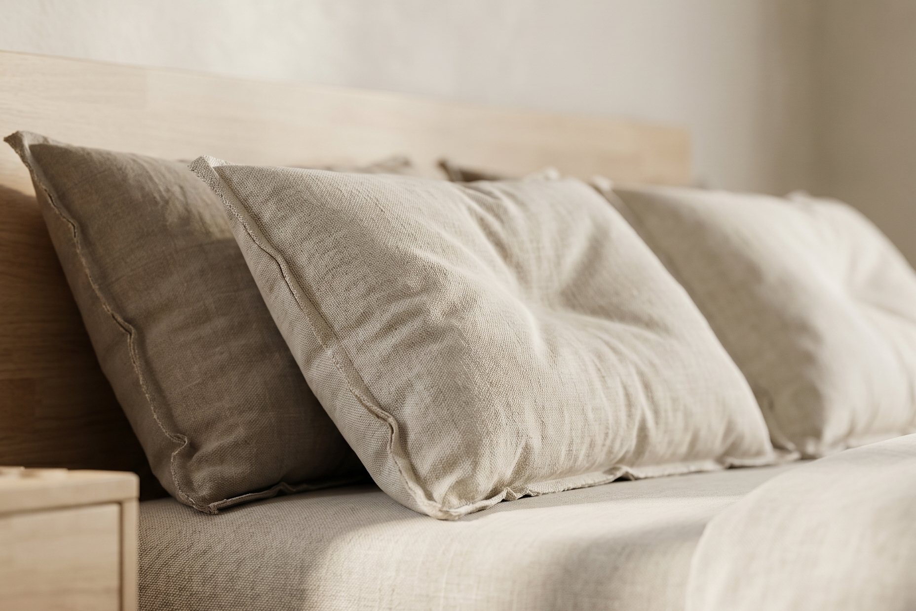 An oak bed with linen pillows, bedding and a matching bedside table